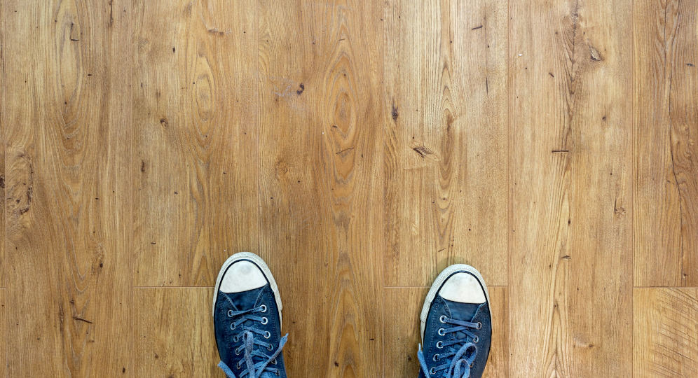 Die Spitze von zwei Schuhen auf einem Dielenboden