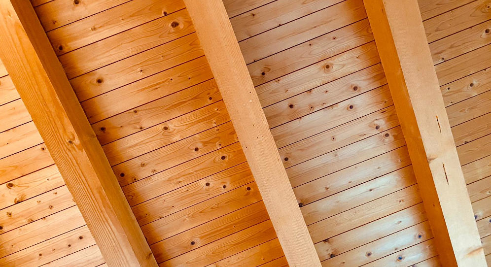 Eine Holzbalkendecke mit Dielenboden von unten